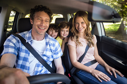 Smiling family sitting in the car, a Photo by wavebreak