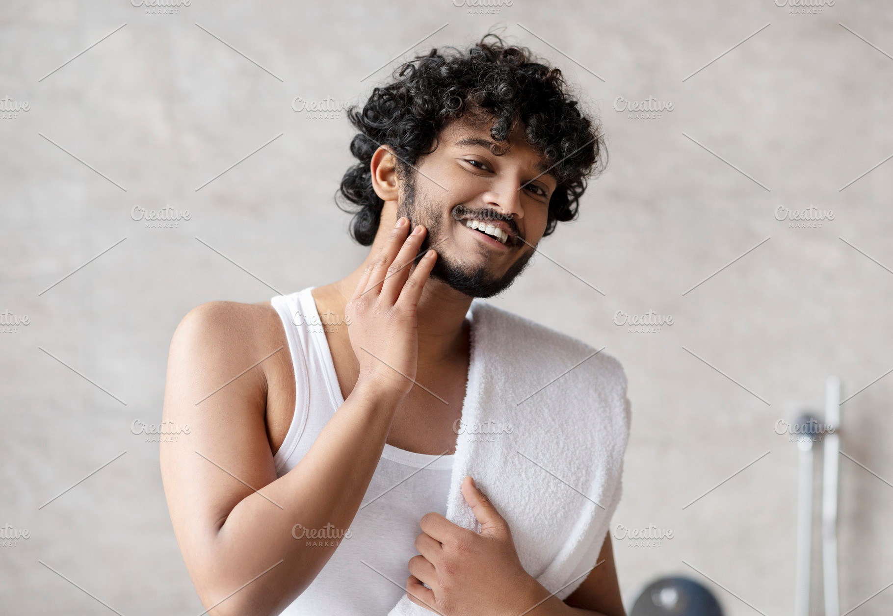 Portrait of happy indian man touching beard and smiling at camera, attractive y, a Person Photo by Prostock-Studio