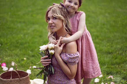 beautiful young mother with a baby daughter in pink dresses sitting on a green, a Person Photo by SaulichPhoto