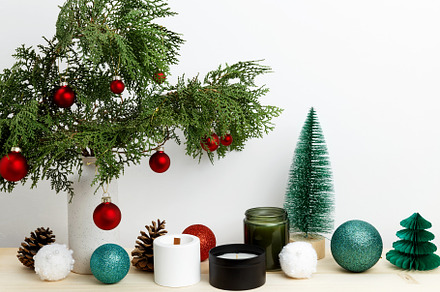 Vase with thuja branches, Christmas ornaments, pinecone, and candle for festive, a Photo by matucha