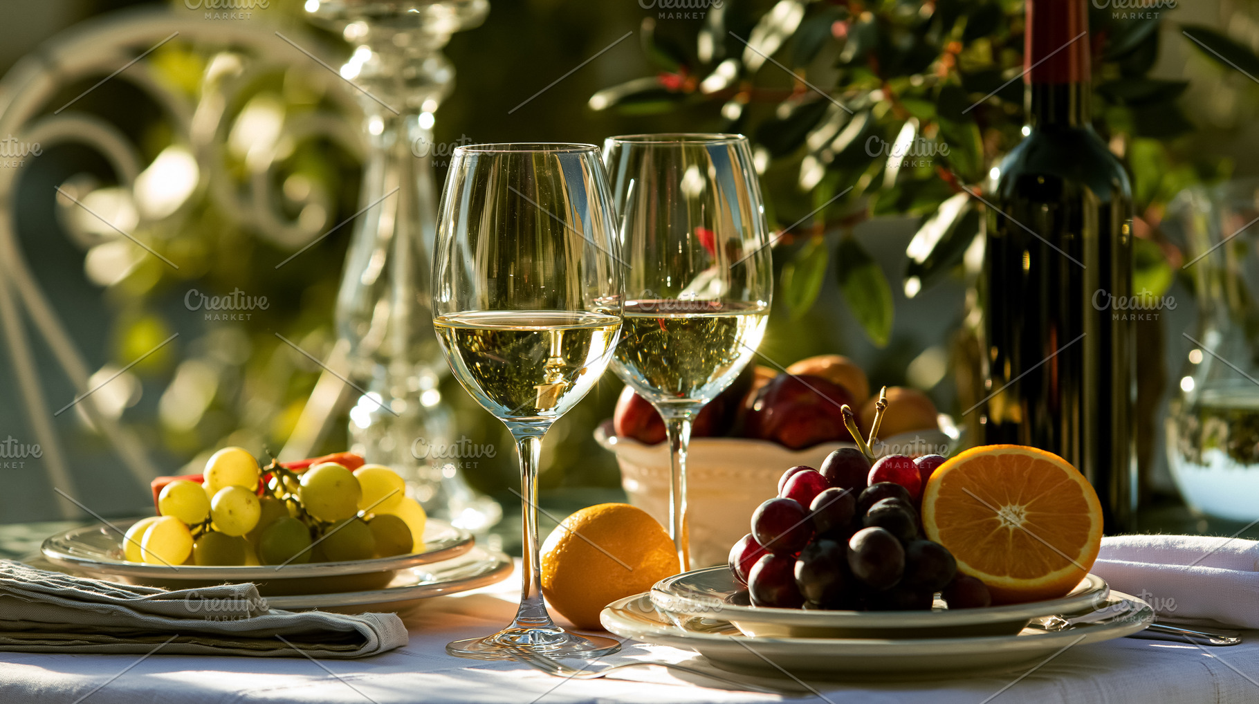 Two white wine glasses and red wine bottle on an outdoor table setting with fre, a Photo by Studio ANNA