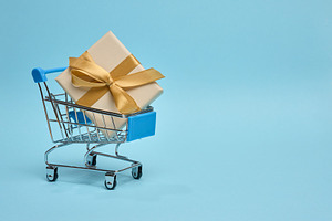 Miniature shopping cart with gift box, beige packaging, blue ba, a Holiday Photo by ndanko