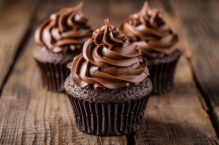 Chocolate cupcakes with whipped cream on wooden table, a Food & Drink Photo by AlyaAnd