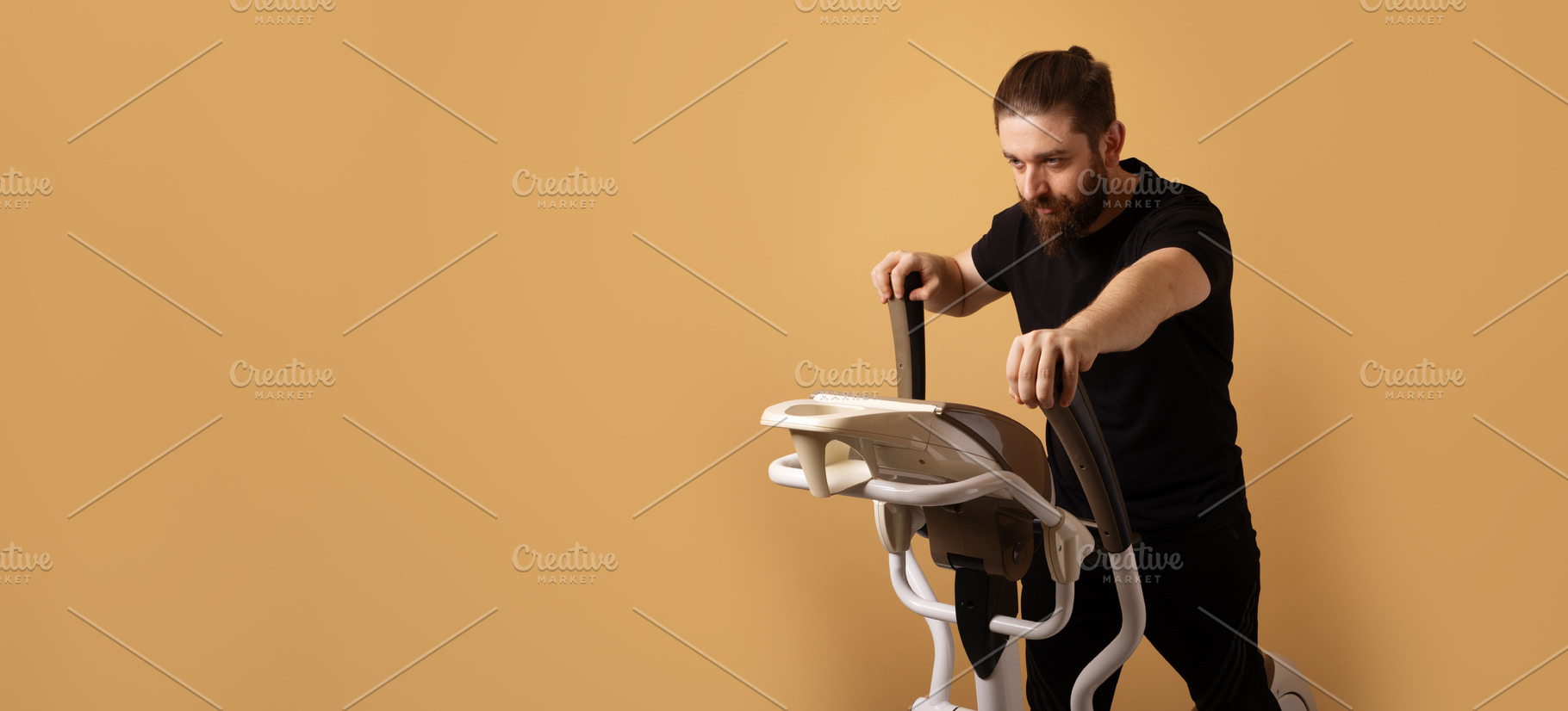 Bearded man in black sportswear using an elliptical machine on a, a Person Photo by Ales Munt