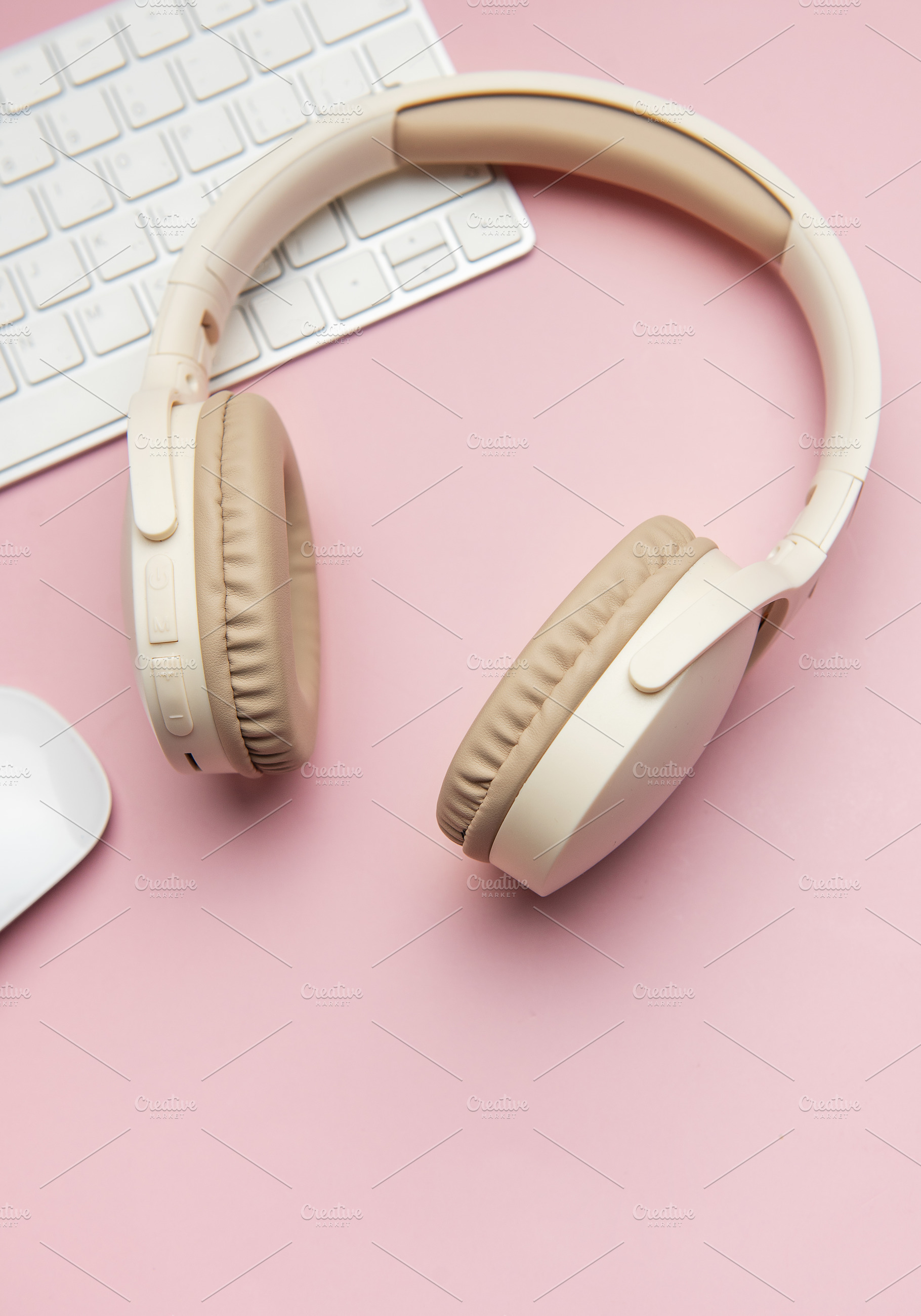 Wireless headphones, keyboard and mouse lying on pink table, a Business Photo by Olena Rudo