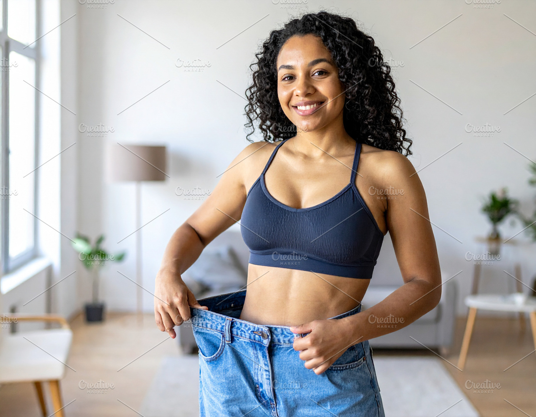 Woman with happy expression tying the waistband of oversized jea, a Health & Medical Photo by DanFLCreativo