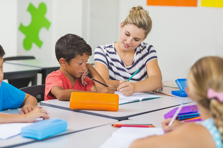 Teacher helping kids with their homework in classroom, a Photo by wavebreak