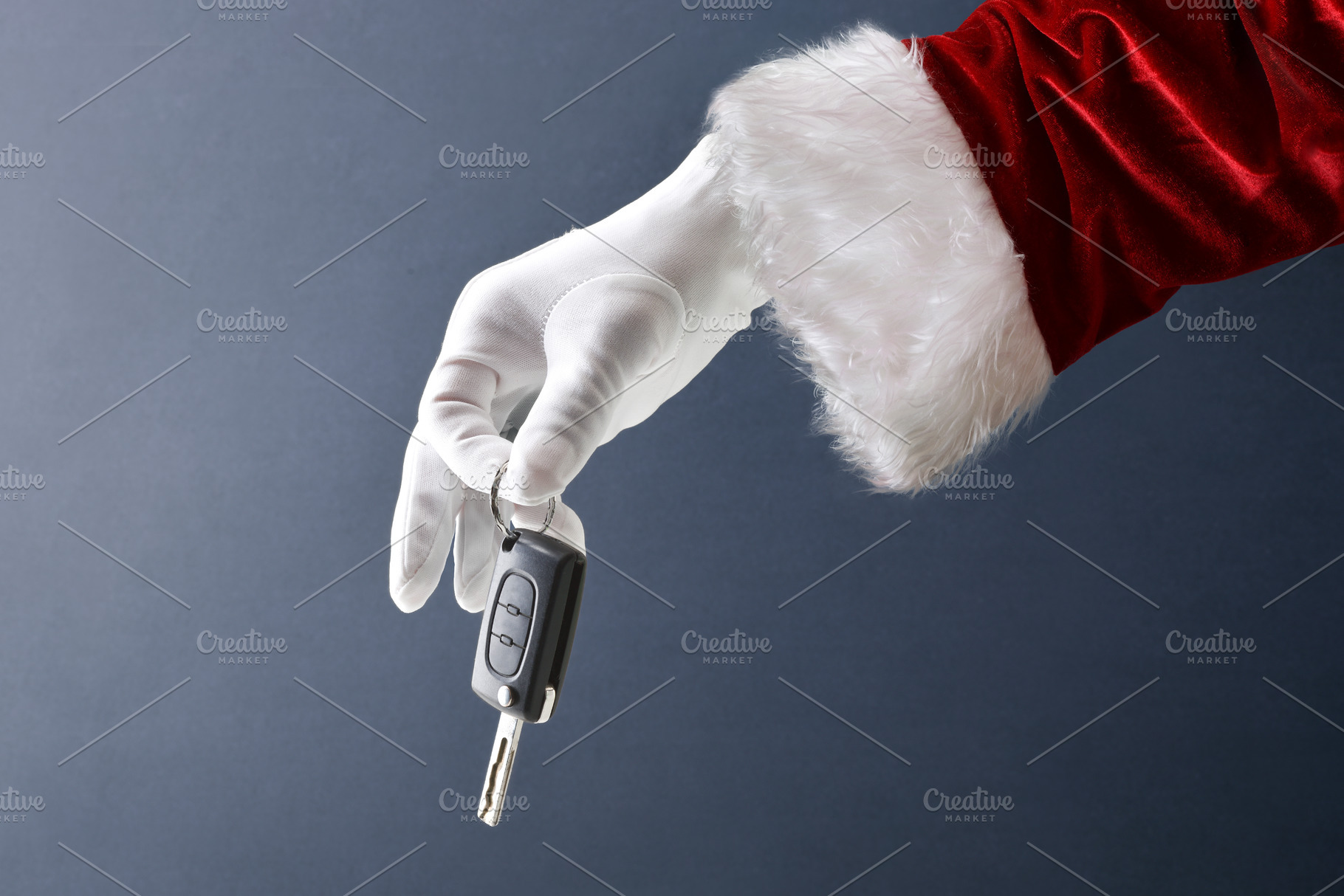 Santa Claus hand holding car key isolated on blue background, a Holiday Photo by Davizro's Market