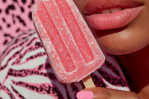 Frosted pink popsicle held near glossy pink lips with matching n, a Photo by José Manuel Gelpi