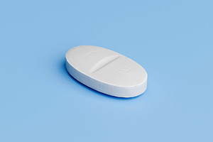 White oval tablet pill on light blue background, a Health & Medical Photo by RF Images