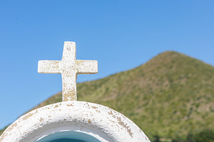 White cross overlooking a green hill under a clear blue sky, a Photo by Antonio Gravante Market