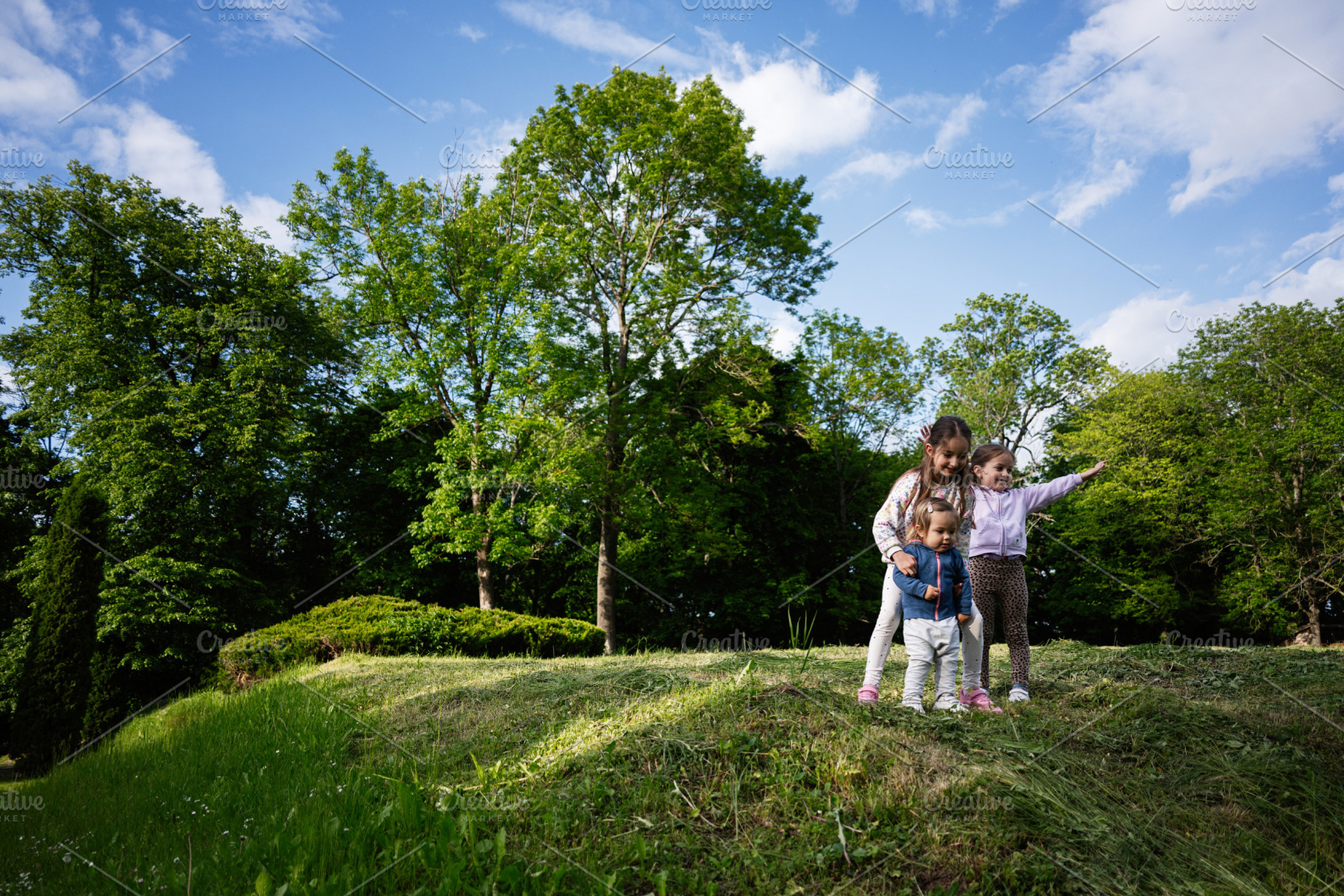 Children playing outdoors in a vibrant green park with blue skies above, a Person Photo by AS photostudio