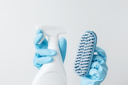 Woman in rubber gloves holding cleaning spray and brush, ready for household cl
