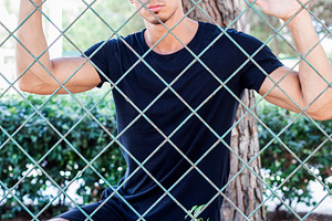 Young man posing behind chain link fence, a Person Photo by RF Images