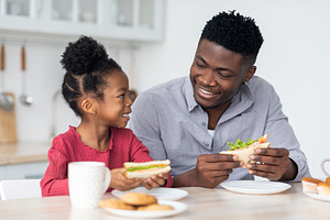 Portrait of loving black family having lunch at home, a Photo by Prostock-Studio