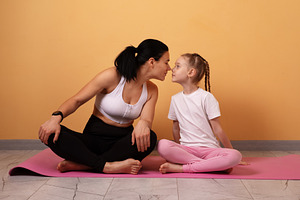 Woman and young girl sitting on yoga mat, facing each other and, a Person Photo by Ales Munt