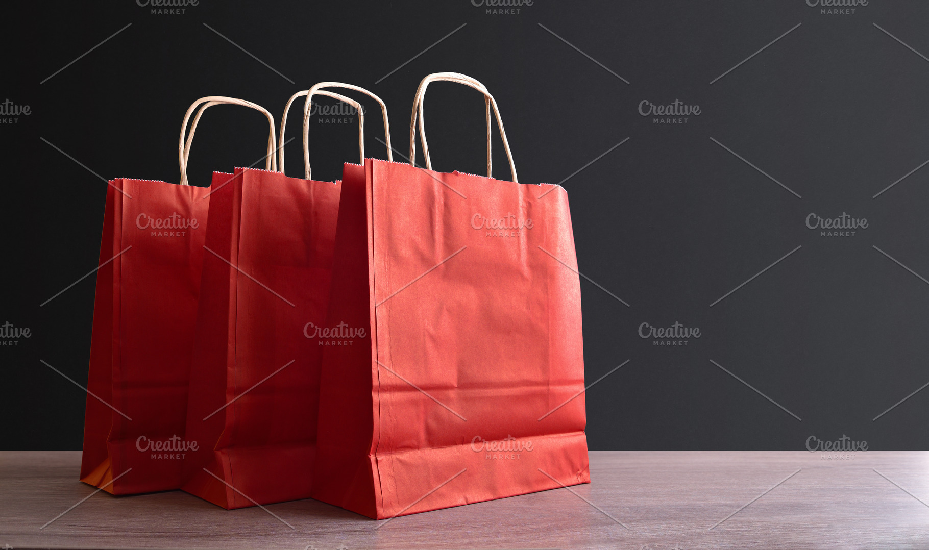 Three red paper shopping bag on wooden and isolated background, an Industrial Photo by Davizro's Market