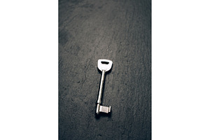 Single old key on dark slate stone, a Business Photo by Anna Efetova
