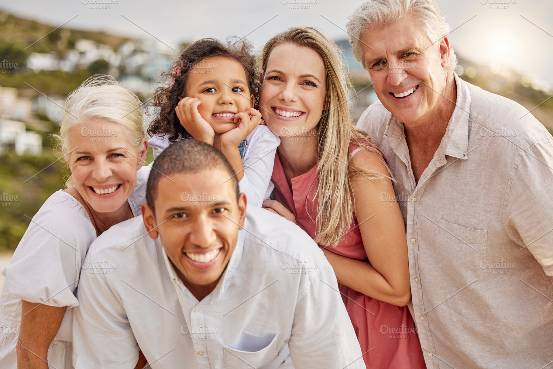 Portrait of a senior caucasian couple at the beach with their children and grandchild. Mixed race family relaxing on the beach having fun and bonding, a Photo by Peopleimages.com