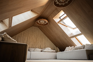 Cozy attic living space with wooden interior and natural light from skylights, a Photo by AS photostudio