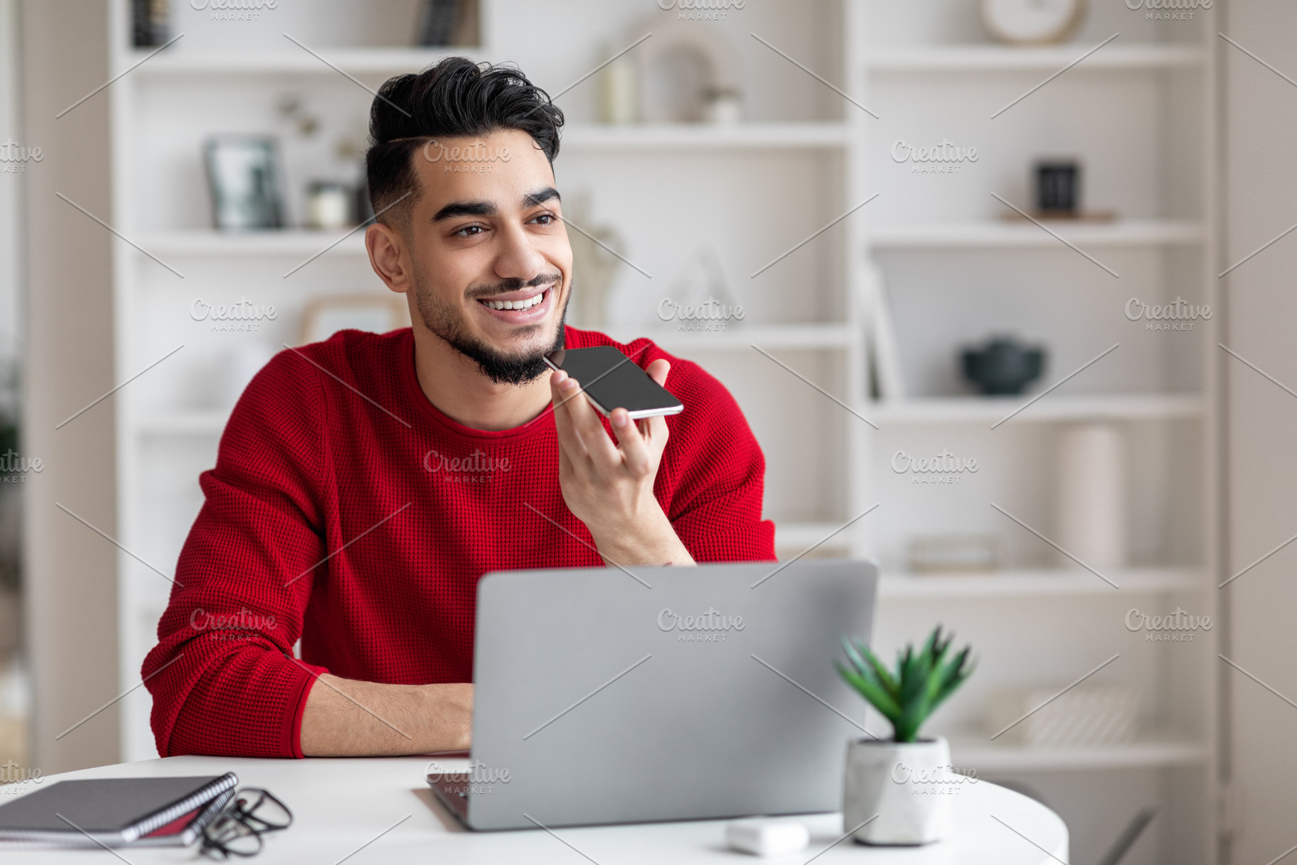 Young Arab Man Using Smartphone For Recording Voice Message At Home, a Photo by Prostock-Studio