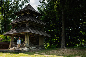 Wooden bell tower surrounded by trees with a person nearby in daylight, a Person Photo by AS photostudio