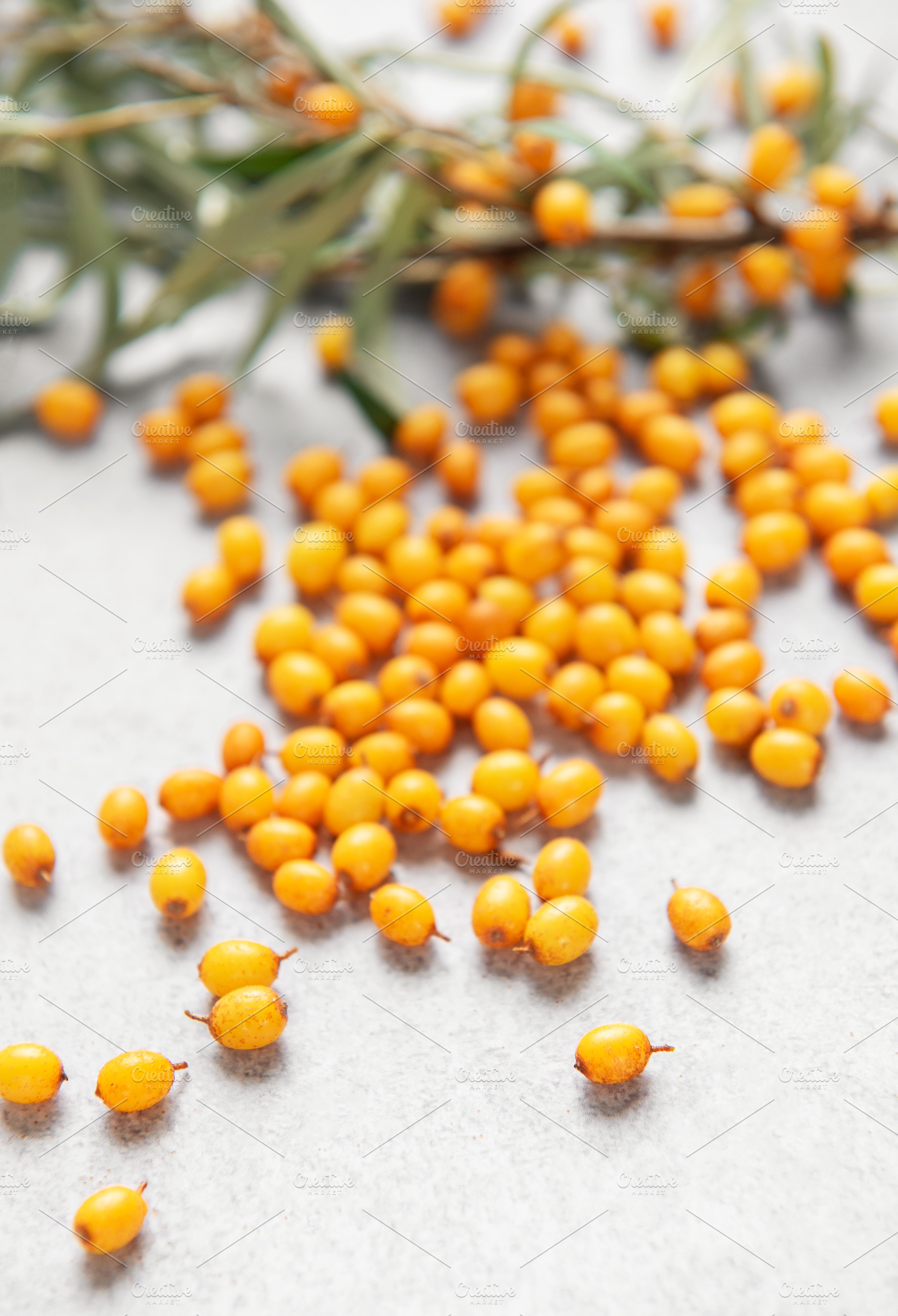 Sea buckthorn berries scattered on gray background, a Food & Drink Photo by Olena Rudo
