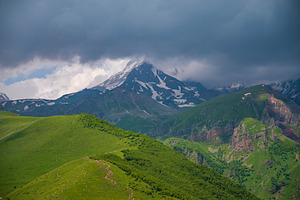 Mount Kazbek in stormy clouds above green ridges of Caucasus wit, a Photo by Pictures for you!!!!!!!!!