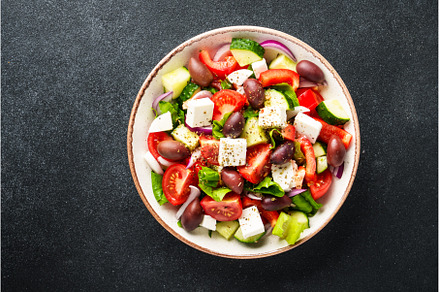 Greek salad in craft plate on black