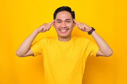 Young man pointing at his forehead, a Person Photo by Sewupari Studio