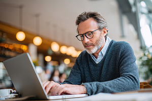 Man in smart casual clothing works remotely in a vibrant cafe during daylight h, a Person Photo by AlyaAnd