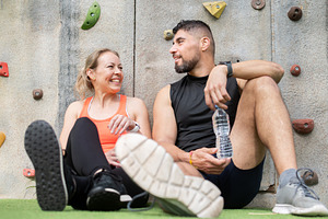 Active couple resting after workout and talking near climbing wall outdoors, a Food & Drink Photo by etorres69