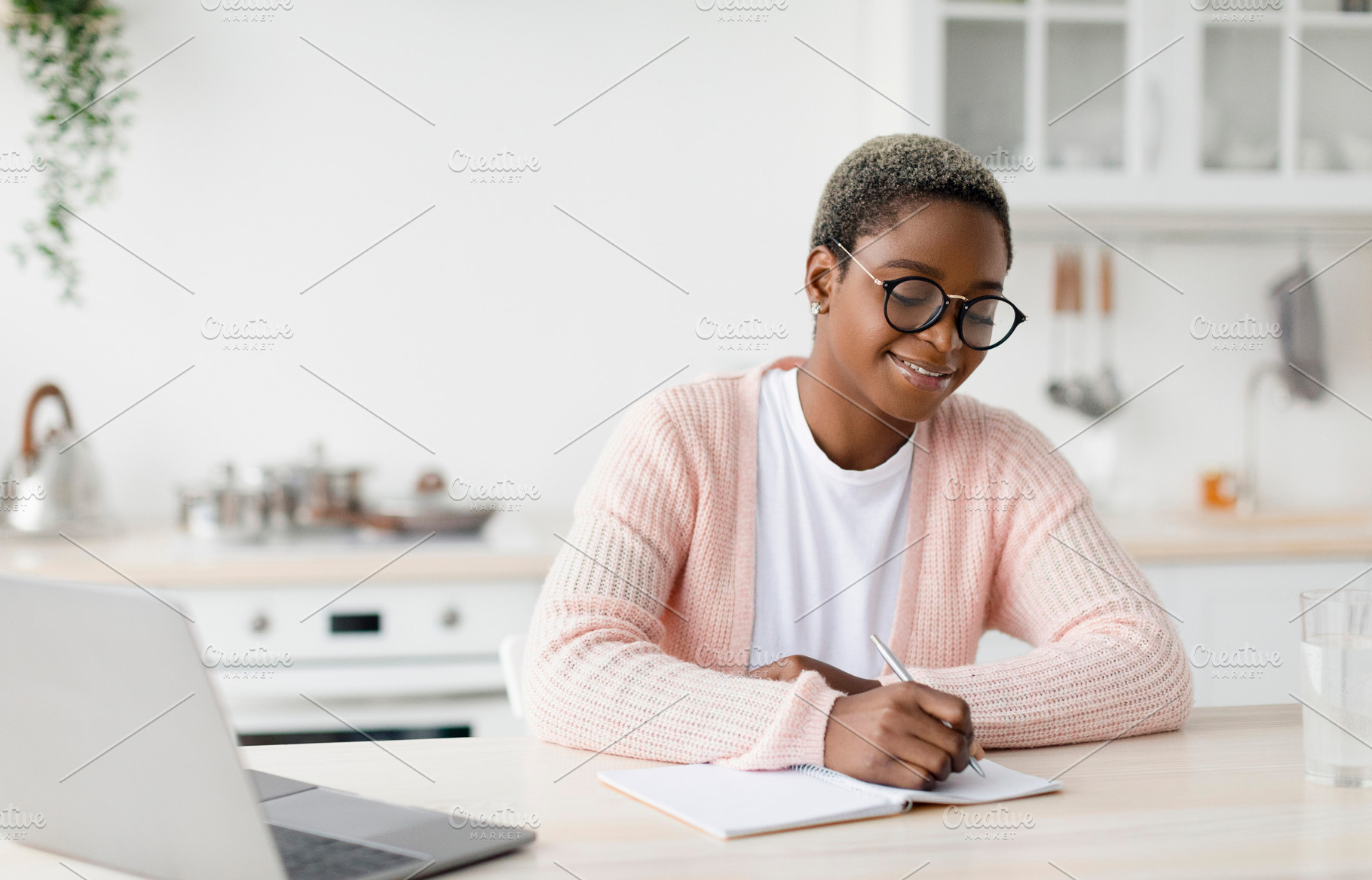 Cheerful millennial pretty black female student or worker in glasses at table w, a Person Photo by Prostock-Studio
