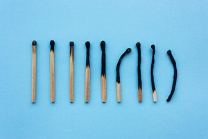 Burned matches in a row on a blue ba containing burned, matches, and concept