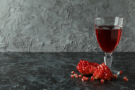 Glass of pomegranate juice and ingredient on black smokey table, a Food & Drink Photo by AtlasStudio