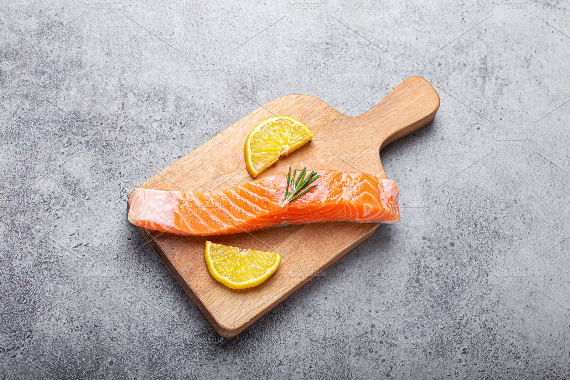 Raw salmon fish fillet with lemon wedges and rosemary on wooden, a Food & Drink Photo by its_al_dente