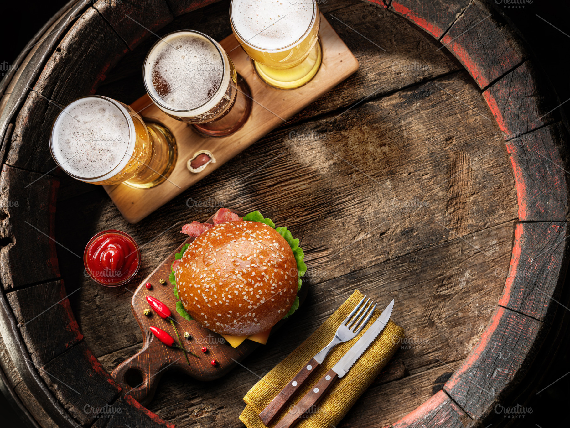 Three glasses of lager beer and hamburger on old wooden barrel., a Food & Drink Photo by Volff
