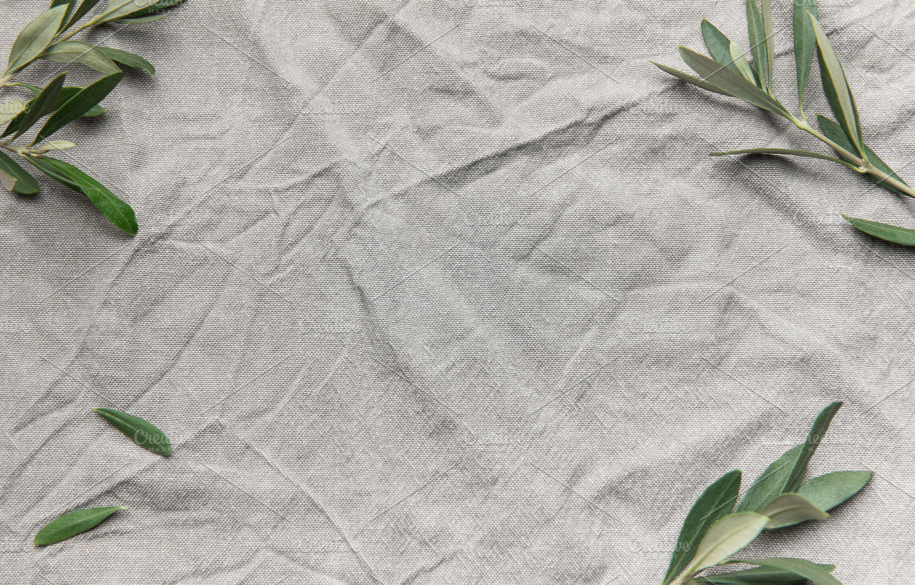 Olive branches framing wrinkled gray linen cloth background, a Background Photo by Olena Rudo