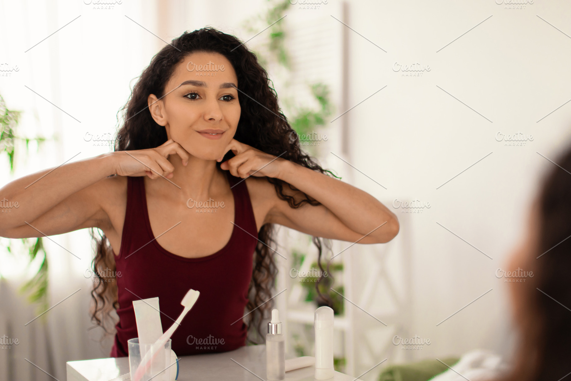 Beautiful young woman making lymphatic drainage self massage, sculpting jaw lin, a Photo by Prostock-Studio