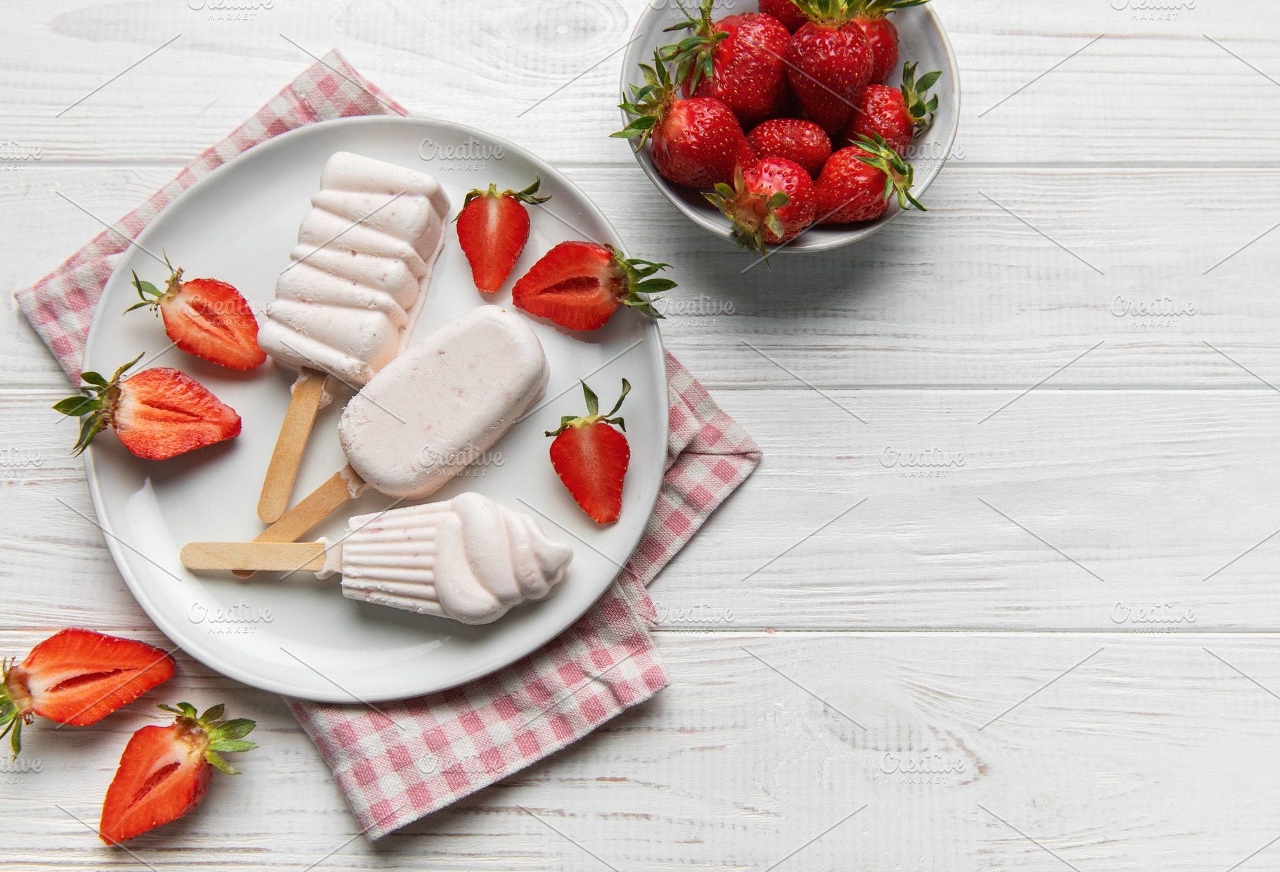 Homemade strawberry ice cream popsicles on white wood, a Food & Drink Photo by Olena Rudo