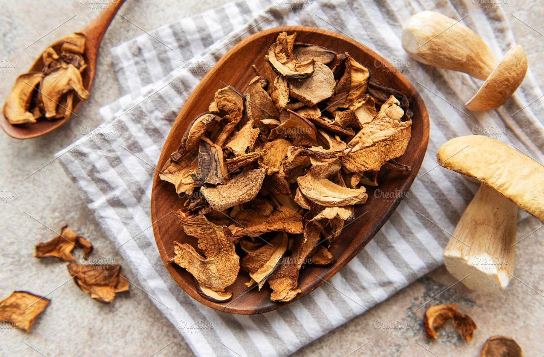 Dried mushrooms on wooden plate with fresh mushrooms and kitchen, a Food & Drink Photo by Olena Rudo