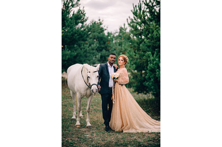 Newlyweds are standing near a white stock photo containing couple and lovers, a Person Photo by Maksym Zaitsev