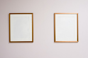 Two empty golden picture frames hanging on a blank wall, presenting a simple ar, a Photo by Studio ANNA