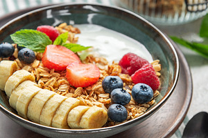 Healthy breakfast bowl with yogurt, granola, banana, and berries, a Food & Drink Photo by Olena Rudo