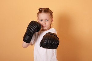 Determined young girl in boxing gloves posing in fighting stance, a Person Photo by Ales Munt