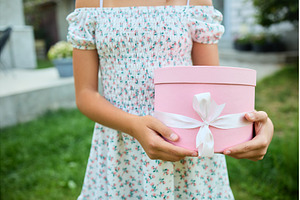 Young girl holds gift box in garden, a Nature Photo by IlliaBondarPhotography