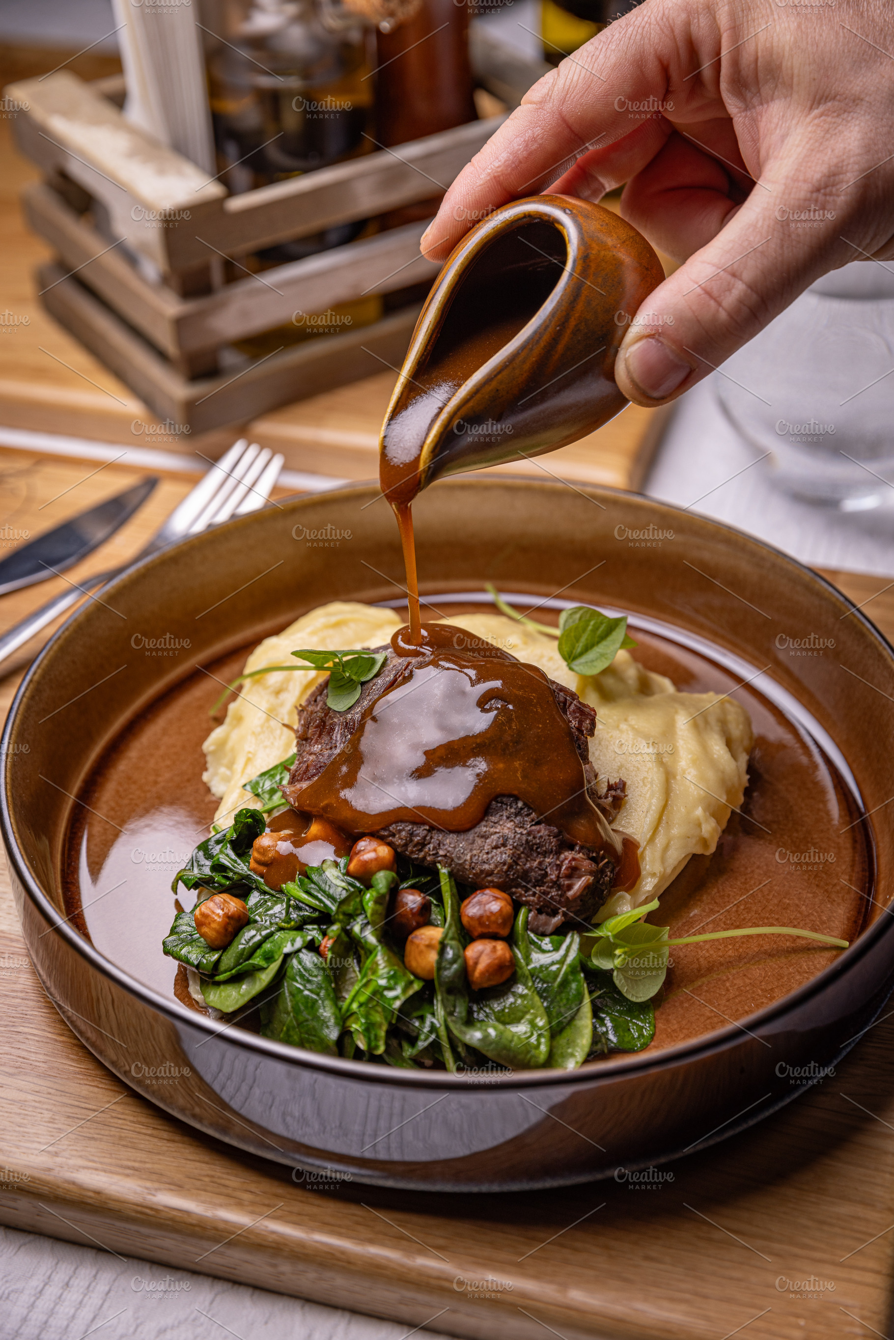 Restaurant chef pouring gravy sauce on a plate, a Photo by Grafvision photography