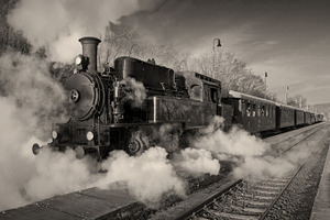 Historic steam train containing locomotive, smoke, and historical