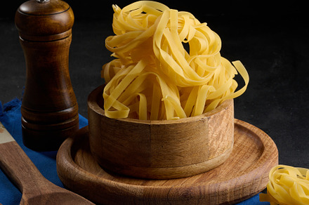 Raw long noodles made from white wheat flour in a wooden bowl on, a Food & Drink Photo by ndanko