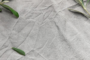 Olive branches framing wrinkled gray linen cloth background, a Background Photo by Olena Rudo